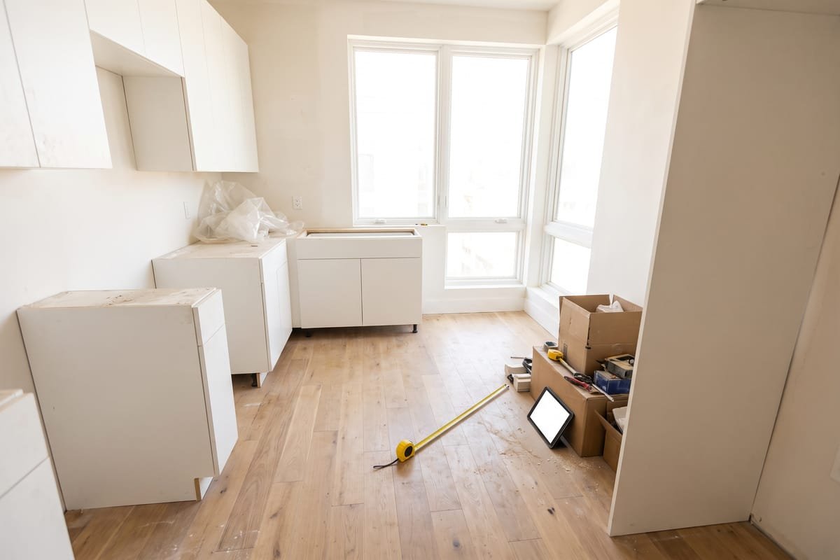 Cozinha vazia de apartamento em obra, com trena e tablet no chão
